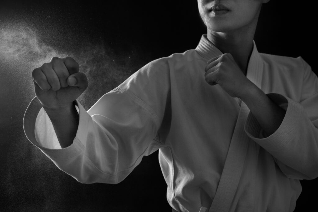 Black-and-white photo of a martial artist holding a strong defensive pose, representing focus, discipline, and confidence.
