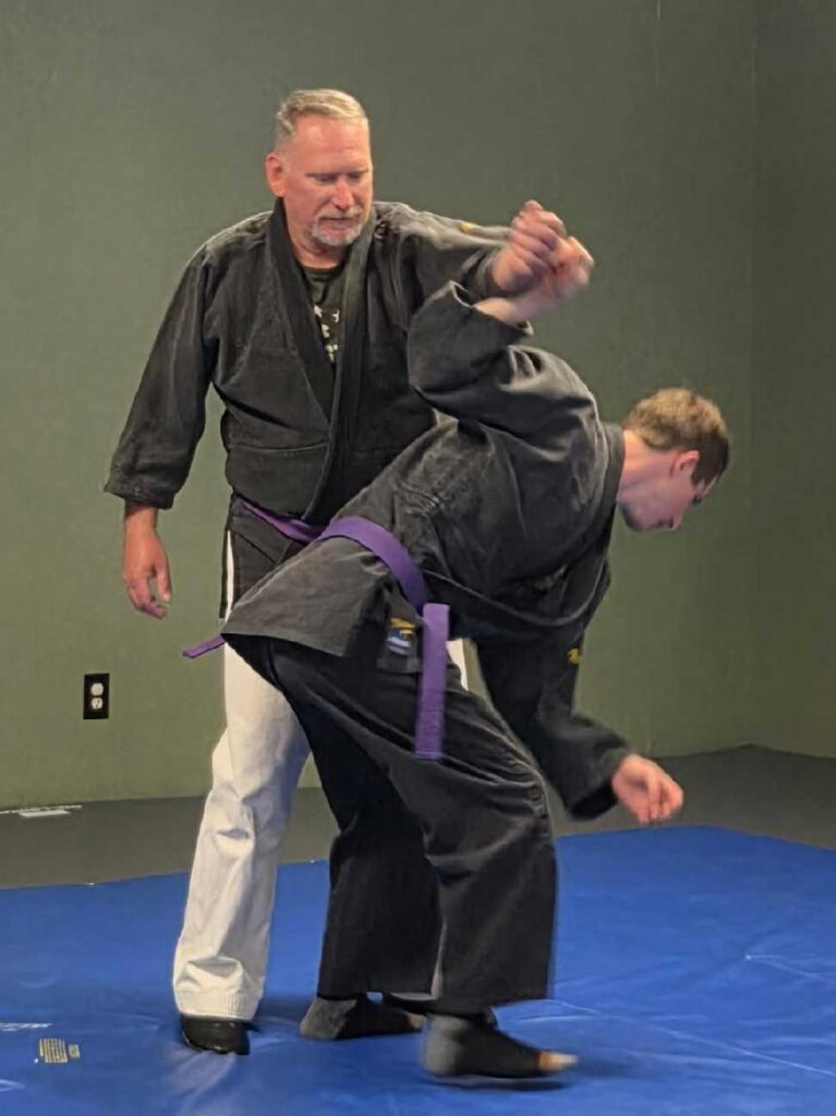 Two students practicing jujitsu techniques during class